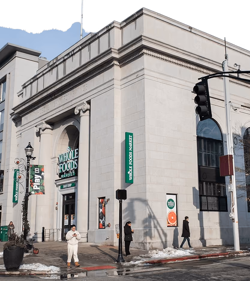 Exterior of a Whole Foods Market store in a classical stone building at a city street corner.