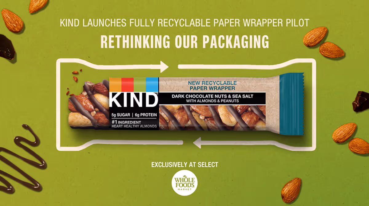 KIND dark chocolate nuts & sea salt bar in new recyclable paper wrapper on green background with almonds.