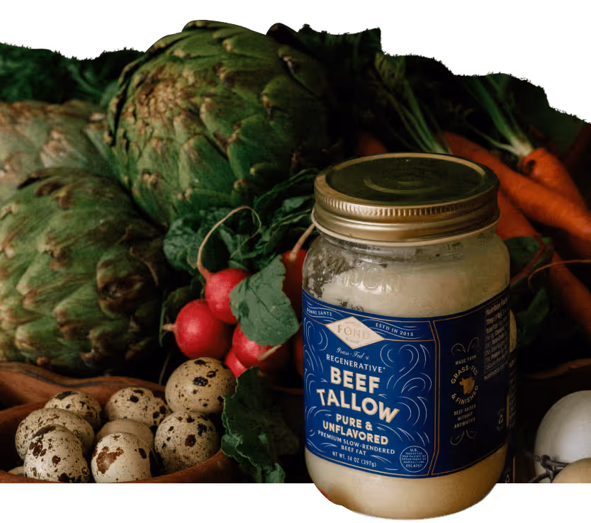 Jar of beef tallow surrounded by artichokes, radishes, carrots, and quail eggs on a dark background.