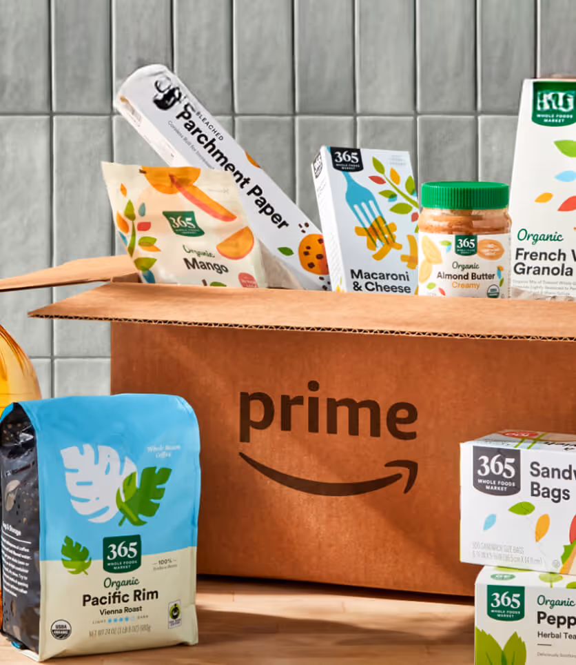 Amazon Prime box filled with 365 Whole Foods Market organic groceries on a wooden table.
